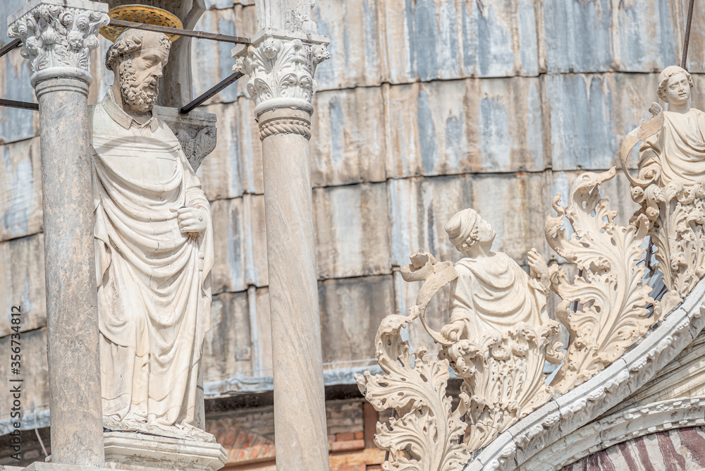 Decoration elements and a saint priest at roof of Basilica San Marco in Venice, Italy, summer
