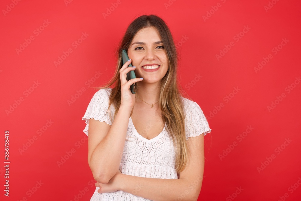 Portrait of a smiling young casual brunette woman talking on mobile phone isolated over white background. Portrait of a smiling young casual brunette woman talking on mobile phone isolated over white background.