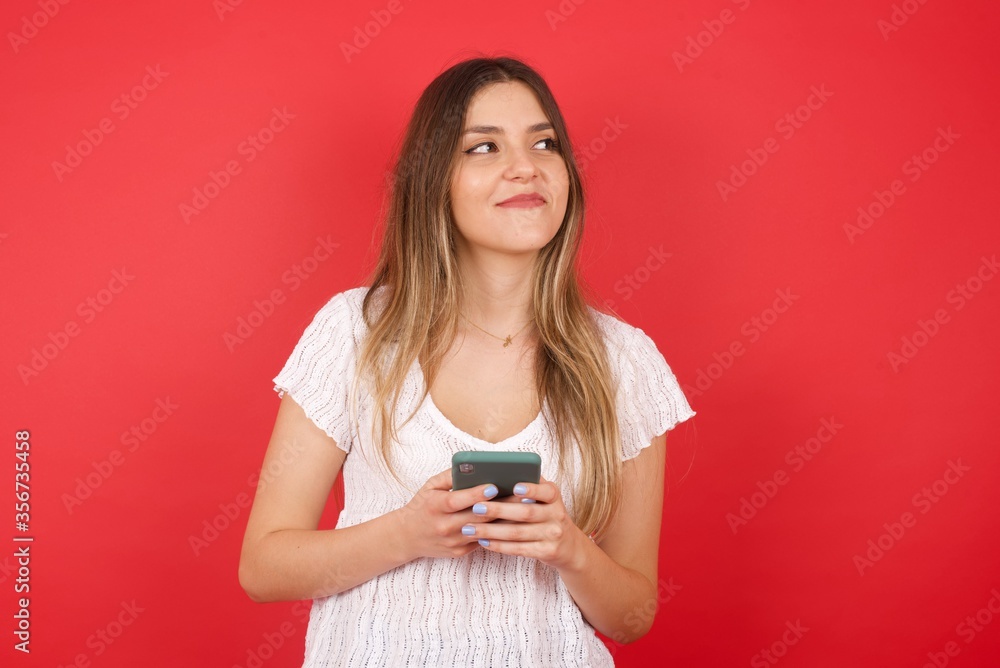 Image of a happy young beautiful woman posing isolated over bright background listening to music with earphones using mobile phone. Image of a happy young beautiful woman posing isolated over bright background listening to music with earphones using mobile phone.