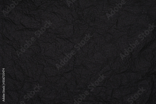 Rumpled embossed closeup napkin texture. Black background © Brmstrff