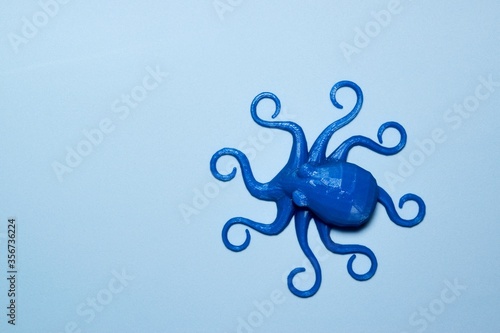 Blue plastic toy octopus on plain light blue background with copy space in a pretend ocean. They symbolize intelligence, flexibility, emotions, logic, creativity and potential. photo