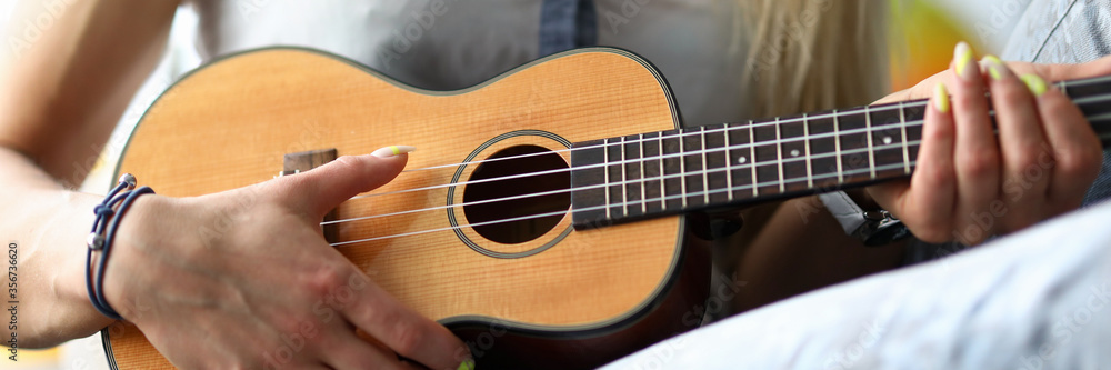 Female hands holding ukulele guitar learning how to play Female hands holding ukulele guitar learning how to play