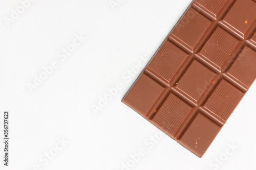 Bar of milk chocolate with nuts inside on white background flat lay top view copy space. Minimalistic Chocolate Background. Chocolate, cocoa, sweet treat, sugar, overweight, chocolate addiction