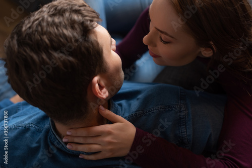 top view of girl touching neck of man in living room