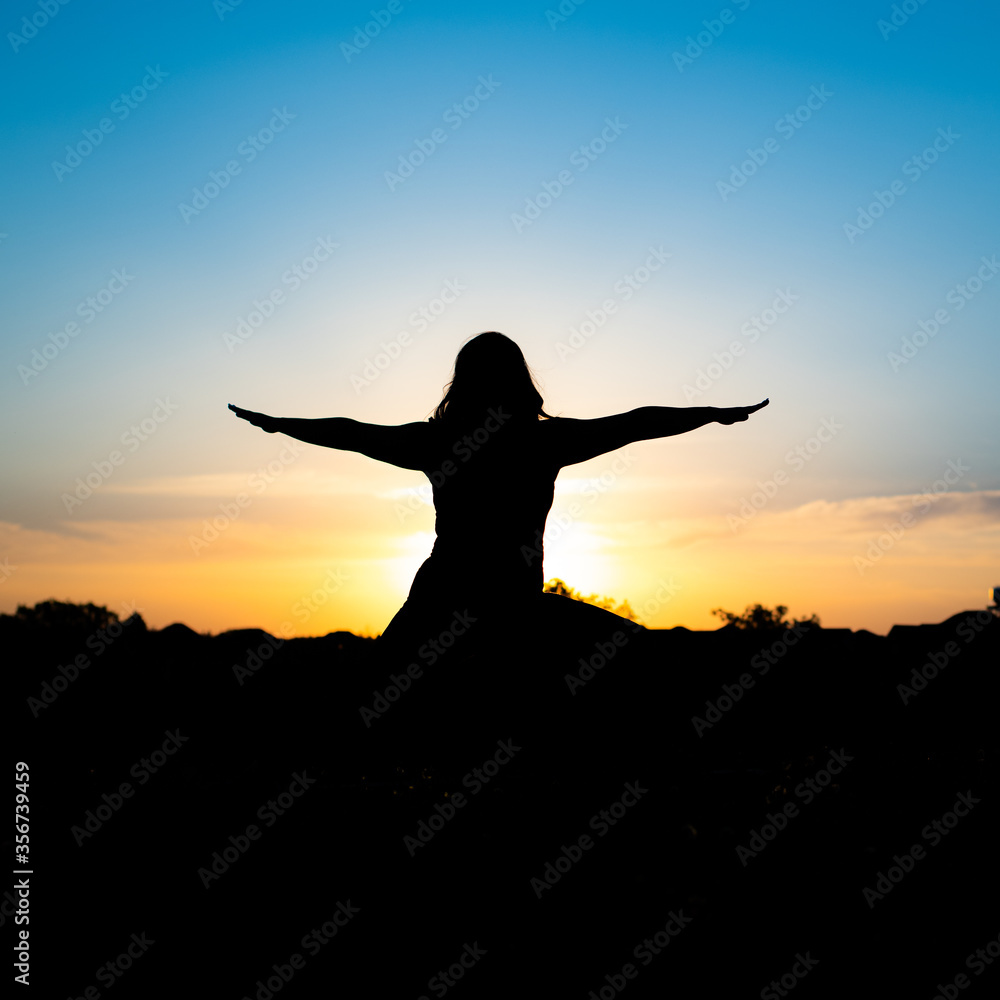 Fototapeta premium silhouette of woman doing yoga in the sunset