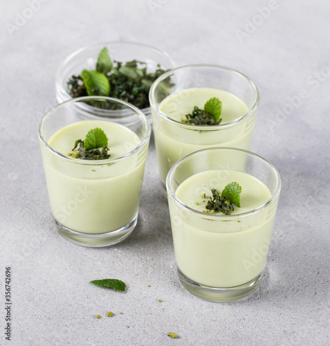 Dessert cream Panna cotta with green matcha tea in a glass on a light background