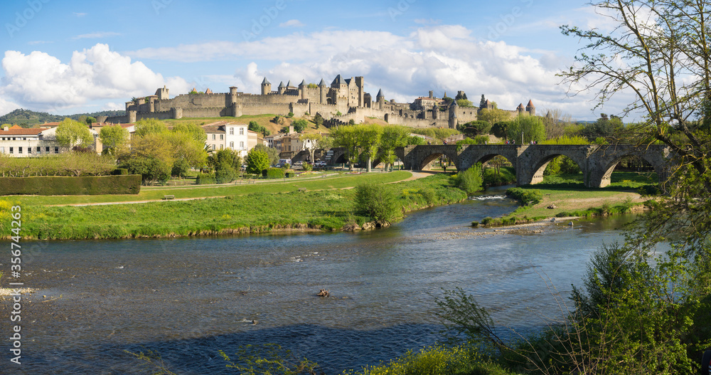 Panorama von Carcassonne mit Fluss in der Sonne unter bewölktem Himmel, Südfrankreich