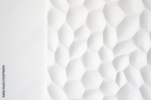 White wall with a wavy texture. Gypsum panels with geometric patterns. Embossed wall in neutral color. Regular repeat cells. Decorative panel made of stone. The texture of the shell.