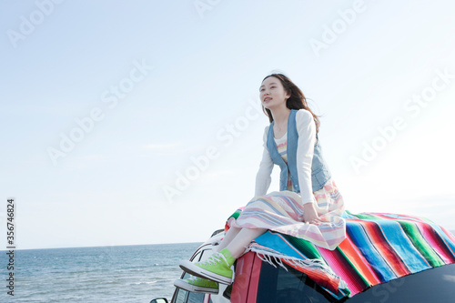 海沿いにとめた車の上に乗る10代の女の子 photo