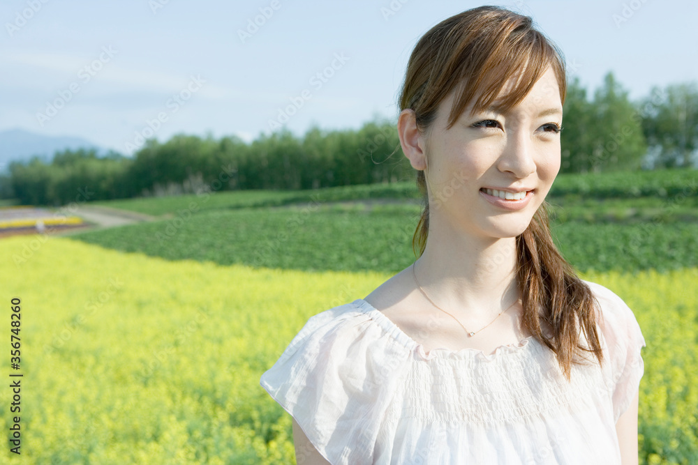 野原にたたずむ笑顔の20代女性 野原にたたずむ笑顔の20代女性