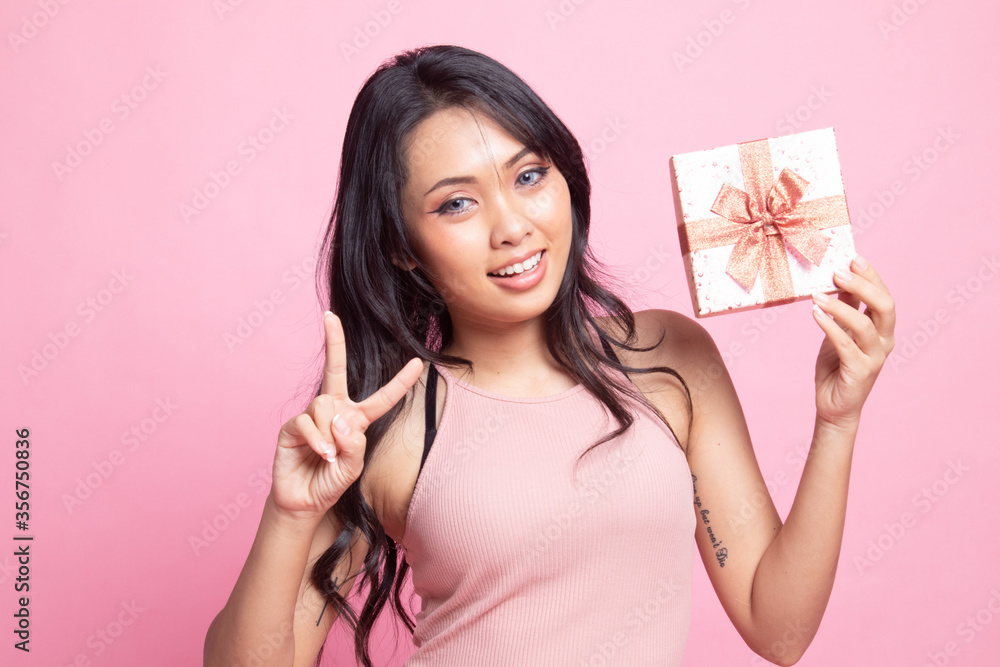 Asian woman show victory sign with a gift box. Asian woman show victory sign with a gift box.
