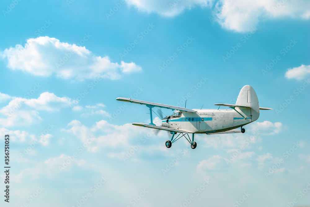 Small old private plane flying in light white clouds
