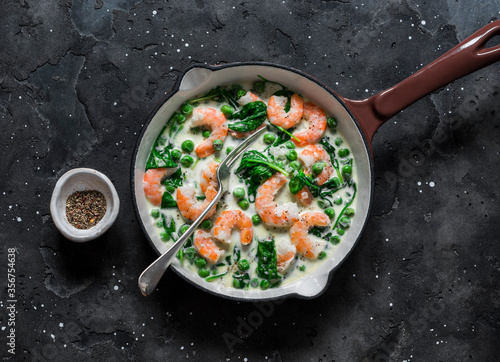 Fotografia Fresh green peas, shrimps, spinach, cream sauce in a cooking pan on a dark backg