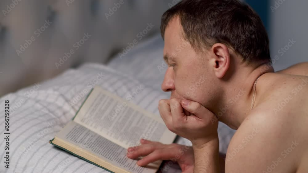 A man reads a book before bedtime, lying in bed A man reads a book before bedtime, lying in bed