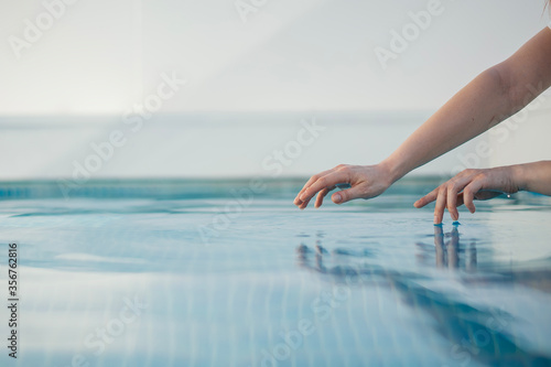 girl hands touch water in the pool
