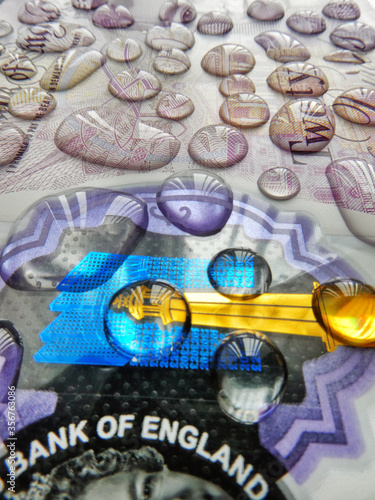 Close up of a twenty pound note covered with water droplets