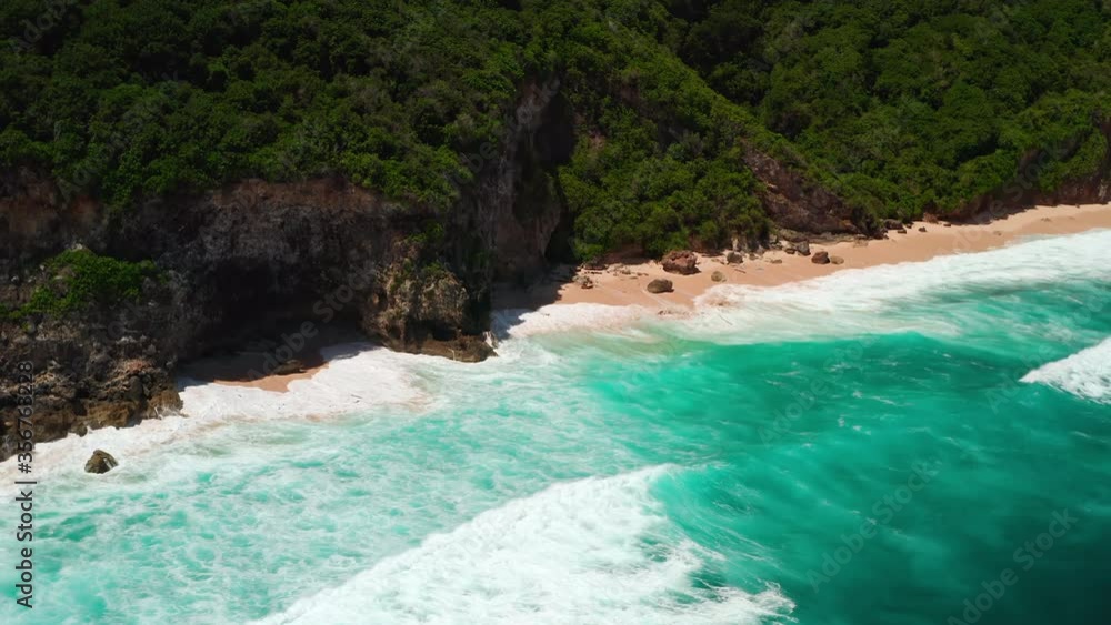 Aerial top view of ocean blue waves break on a beach. Sea waves and beautiful sand beach aerial view drone shot. Bird's eye view of ocean waves crashing against an empty sand beach from above. Aerial top view of ocean blue waves break on a beach. Sea waves and beautiful sand beach aerial view drone shot. Bird's eye view of ocean waves crashing against an empty sand beach from above.