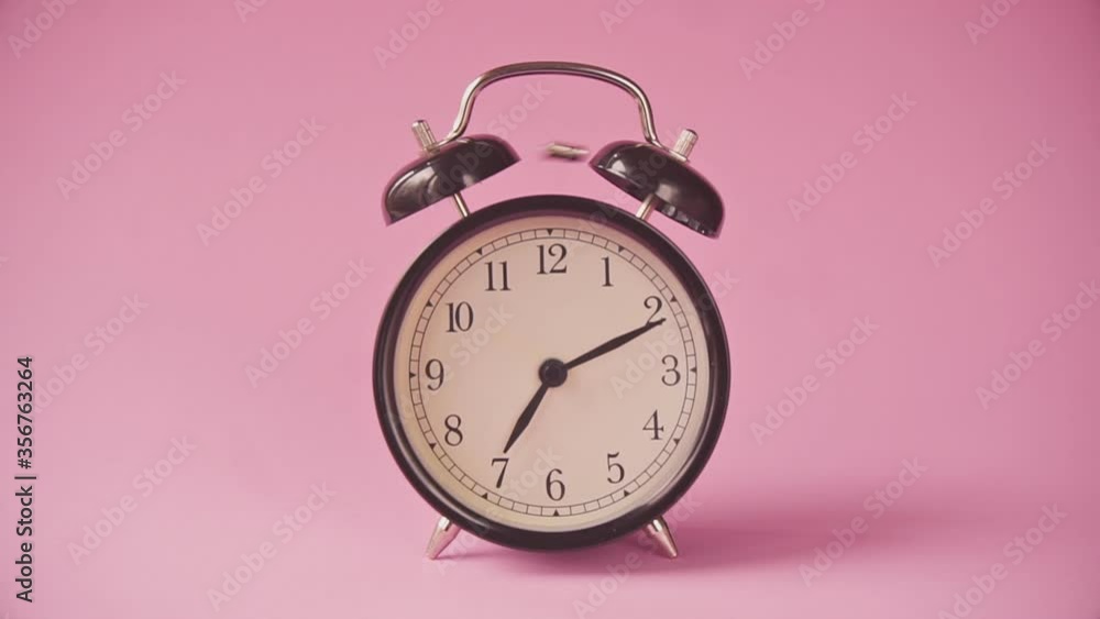 Black alarm clock on a pink background. Black alarm clock on a pink background.