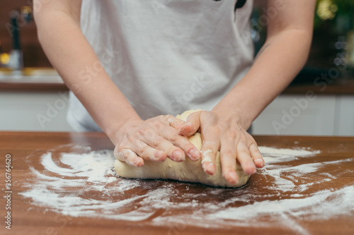 girl kneads dough on a wooden table in the kitchen  © KoshkinS