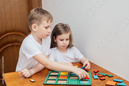 a boy and a girl of European appearance in light clothng sit and play a Board game photo