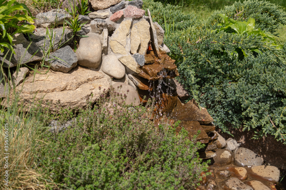 Alpine slide with stones, various ornamental plants and a waterfall Alpine slide with stones, various ornamental plants and a waterfall