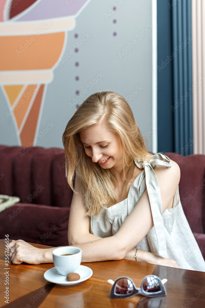 Happy young blond woman sitting in a cafe and drinking coffee during her lunch break. Female portrait Happy young blond woman sitting in a cafe and drinking coffee during her lunch break. Female portrait