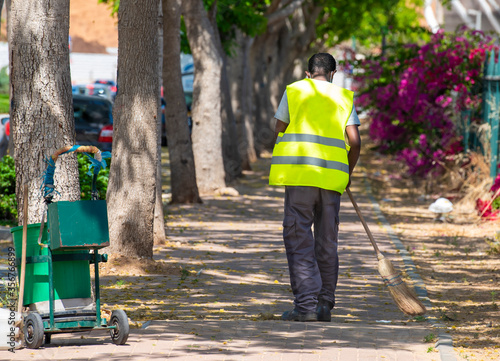 street cleaner with trash can and broom