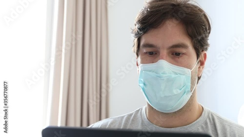Man working in bed, with a facemark, doing home office because he is sick. In 4K photo