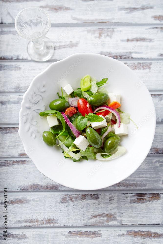 Salad with Green Olives, Cucumber Cherry Tomatoes and Feta Cheese on bright wooden Background. Healthy Snack Idea. Top view. Copy space. Salad with Green Olives, Cucumber Cherry Tomatoes and Feta Cheese on bright wooden Background. Healthy Snack Idea. Top view. Copy space.