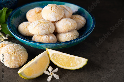 lemon cookies and slices of lemon on a dark table with small white flowers