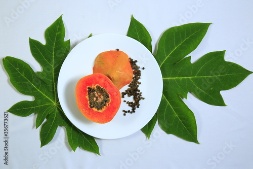 Tasty sweet ripe sliced papaya fruit and seeds in a white bowl with leaves