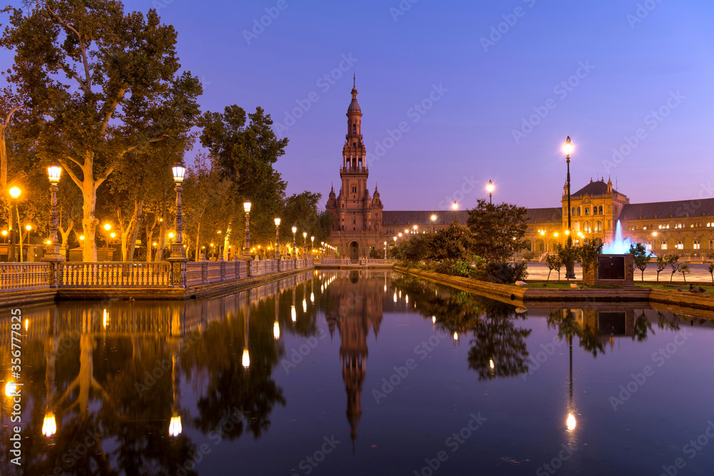 North Tower and Canal - A wide-angle dawn view of the north tower of Plaza de España, reflected in the calm water of the canal, on a clear Autumn morning. Seville, Andalusia, Spain. North Tower and Canal - A wide-angle dawn view of the north tower of Plaza de España, reflected in the calm water of the canal, on a clear Autumn morning. Seville, Andalusia, Spain.
