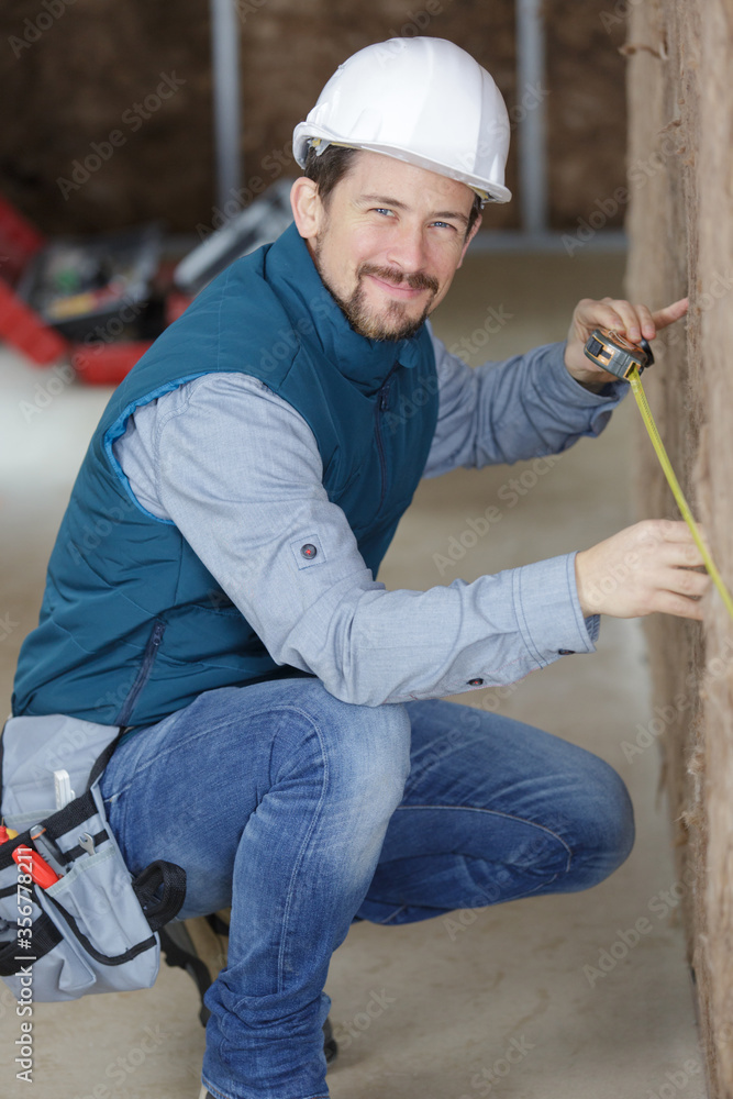 tradesman measuring wall packed with insulation tradesman measuring wall packed with insulation