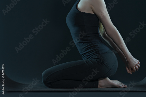 woman practicing yoga pose doing stretching . sport workout fitness. yoga mat and leggins on a dark black background.