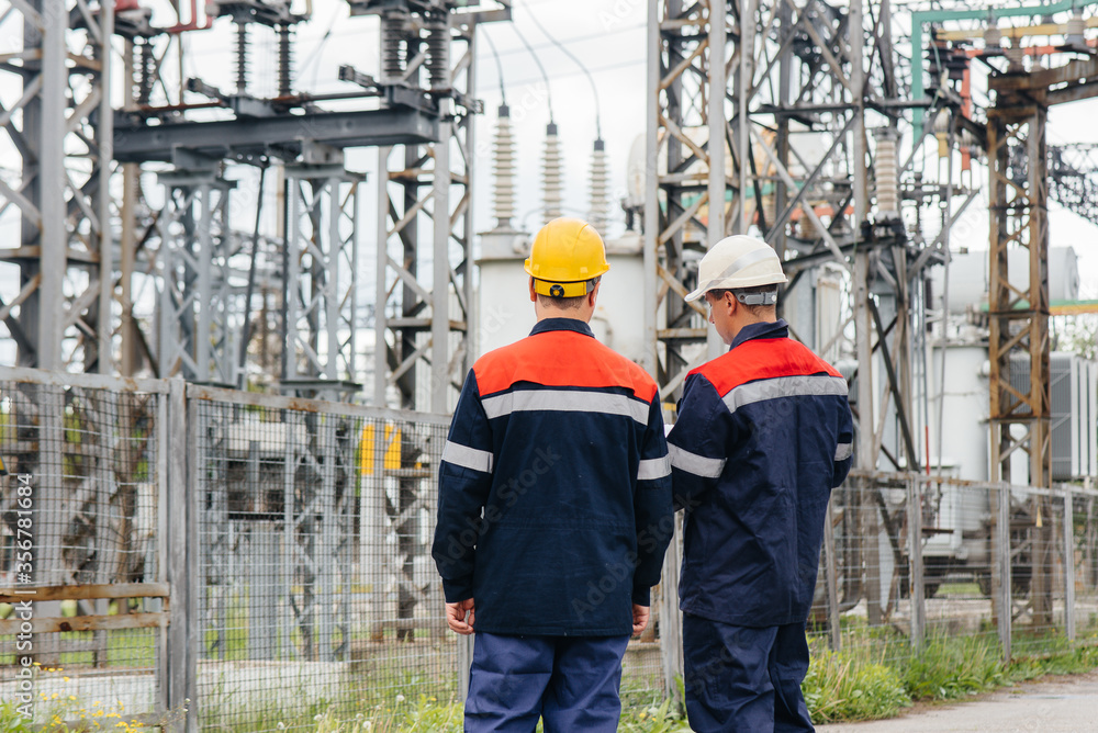 Two specialist electrical substation engineers inspect modern high-voltage equipment. Energy. Industry Two specialist electrical substation engineers inspect modern high-voltage equipment. Energy. Industry