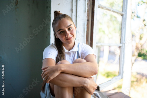 Girl sitting at smiling in a ruined house