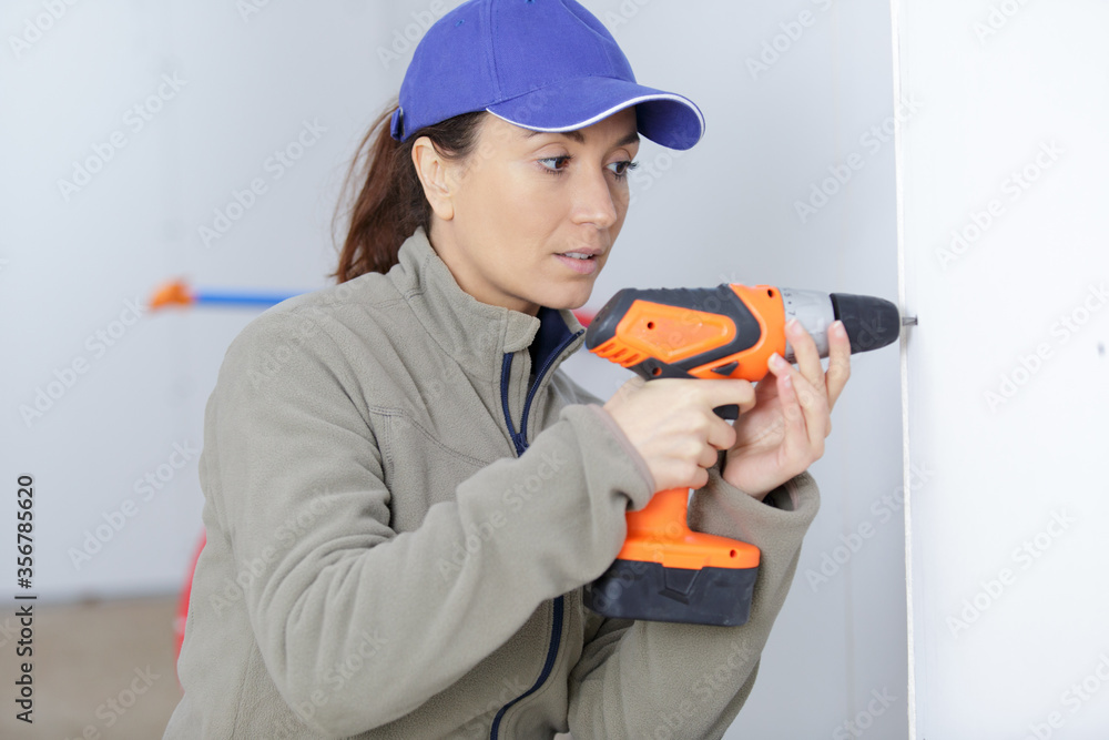woman builder drilling wall in new house woman builder drilling wall in new house