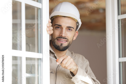 worker screws frame of plastic door