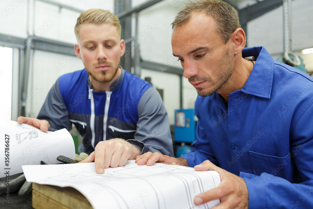 Obraz premium two technicians read a plan in the workshop