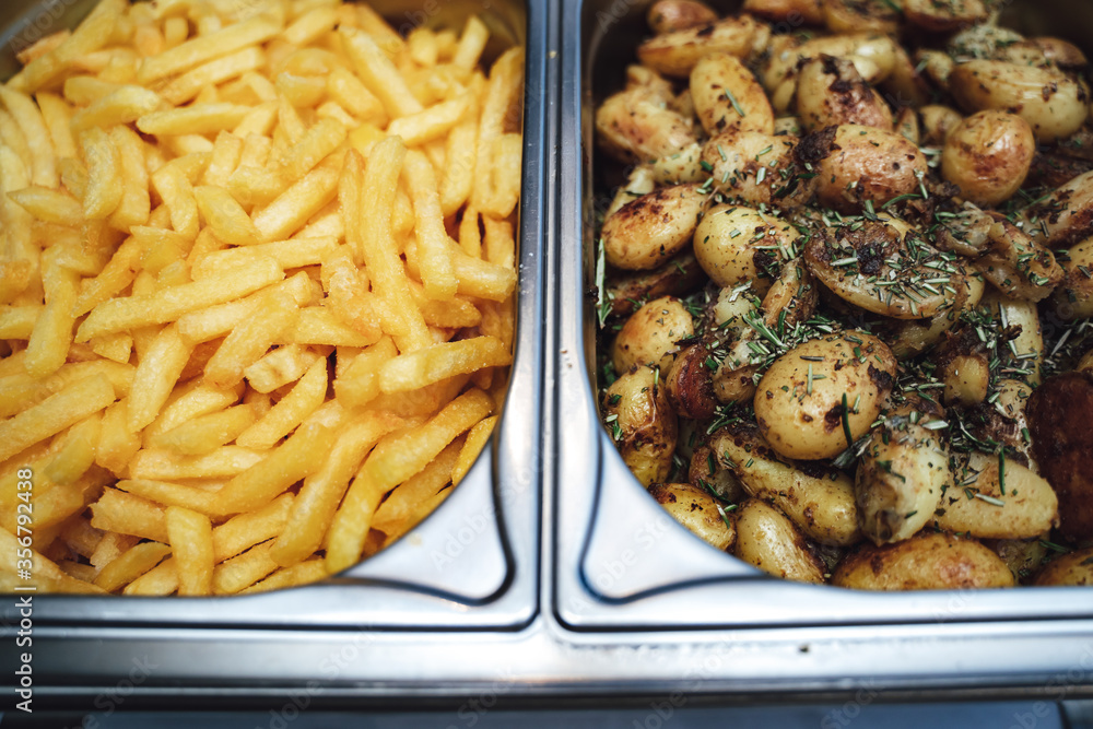 Two potato side dishes in separate hotel pans. French fries and baked potatoes at self-service buffet table. Celebration, party, birthday or wedding Two potato side dishes in separate hotel pans. French fries and baked potatoes at self-service buffet table. Celebration, party, birthday or wedding
