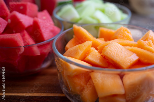 A view of several glass bowls of chopped melon, featuring cantaloupe.