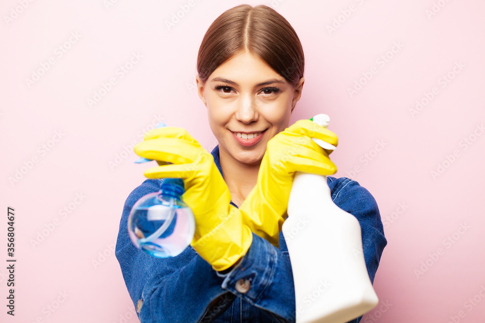 Woman cleaner in overalls and yellow gloves posing on a pink background Woman cleaner in overalls and yellow gloves posing on a pink background