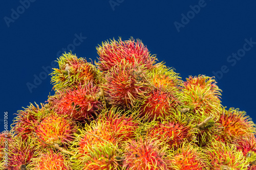 Exotic fruit rambutan presented in the form of a heap on a blue background