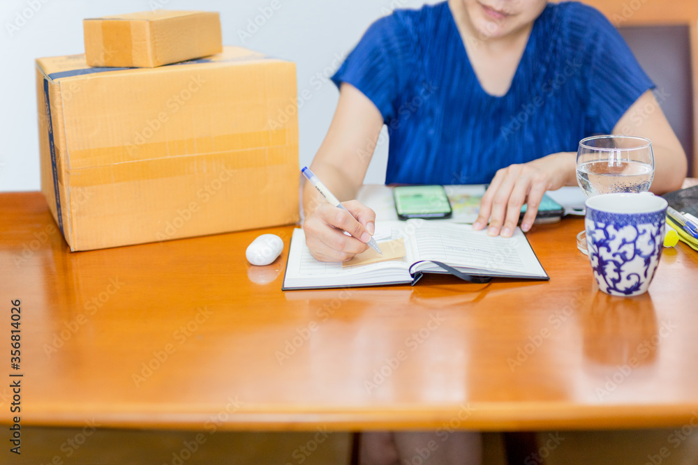 Woman write paper note for delivery package to customer from home office. Woman write paper note for delivery package to customer from home office.