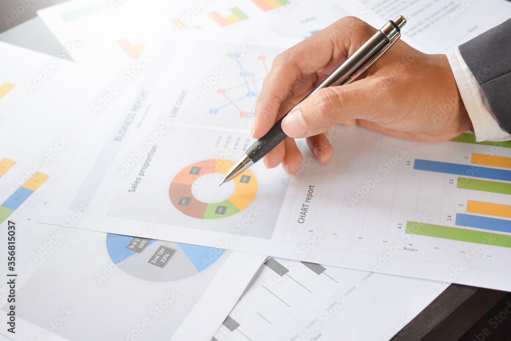 The hand is holding the pen and analyzing the graph,
Businessman analyze graph report on table The hand is holding the pen and analyzing the graph,
Businessman analyze graph report on table