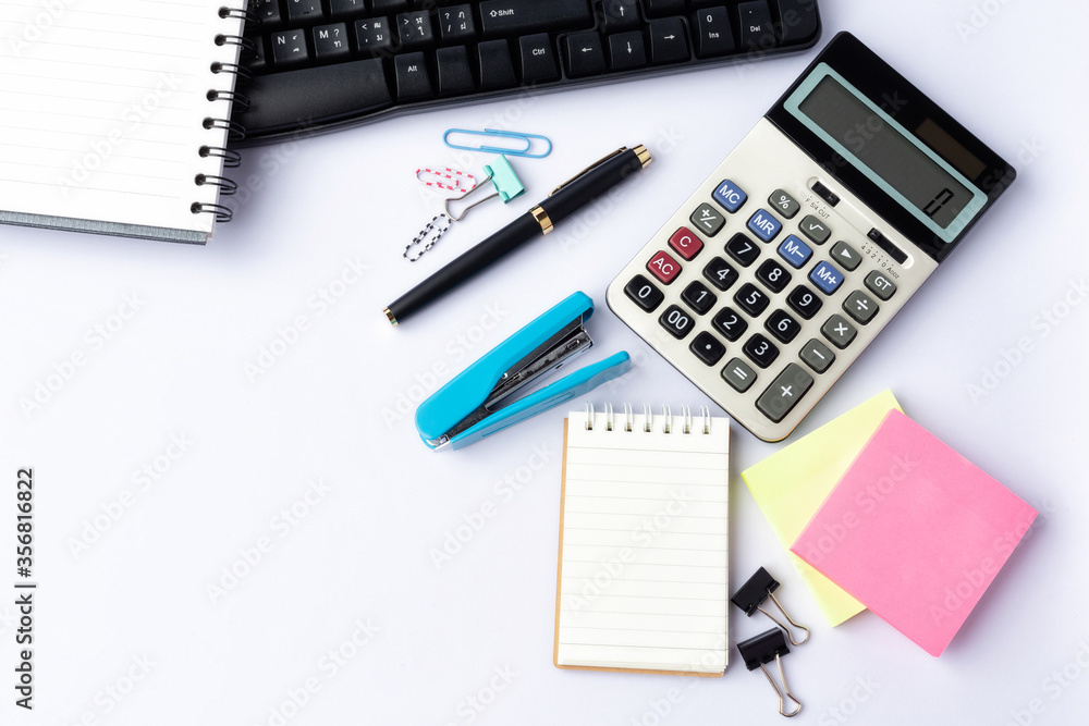 Pen, calculator, keyboard, paper clips on notebook on white background Pen, calculator, keyboard, paper clips on notebook on white background