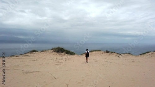 Girl walking on Witsand beach with stormy weather on horizon. Handheld photo