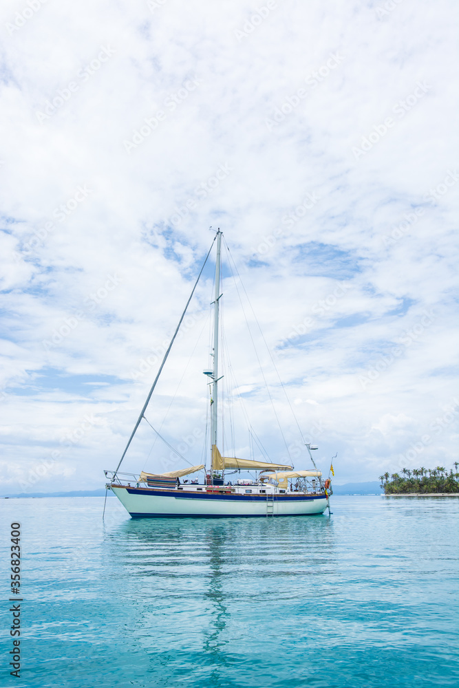 Beautiful seascape of blue sea with floating yacht and white cloud sky. luxury summer day lifestyle vacation tourism travel in Guna Yala, San Blas Islands, Panama, Central America - Vertical shot