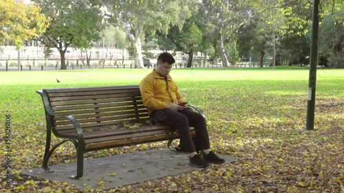 Alone men with yellow jacket using smartphone in the park of the fall season in Melbourne, Australia 2020.