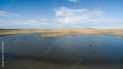 Rural landscape. Aerial view of the blue lake  sky and yellow meadow in autumn.